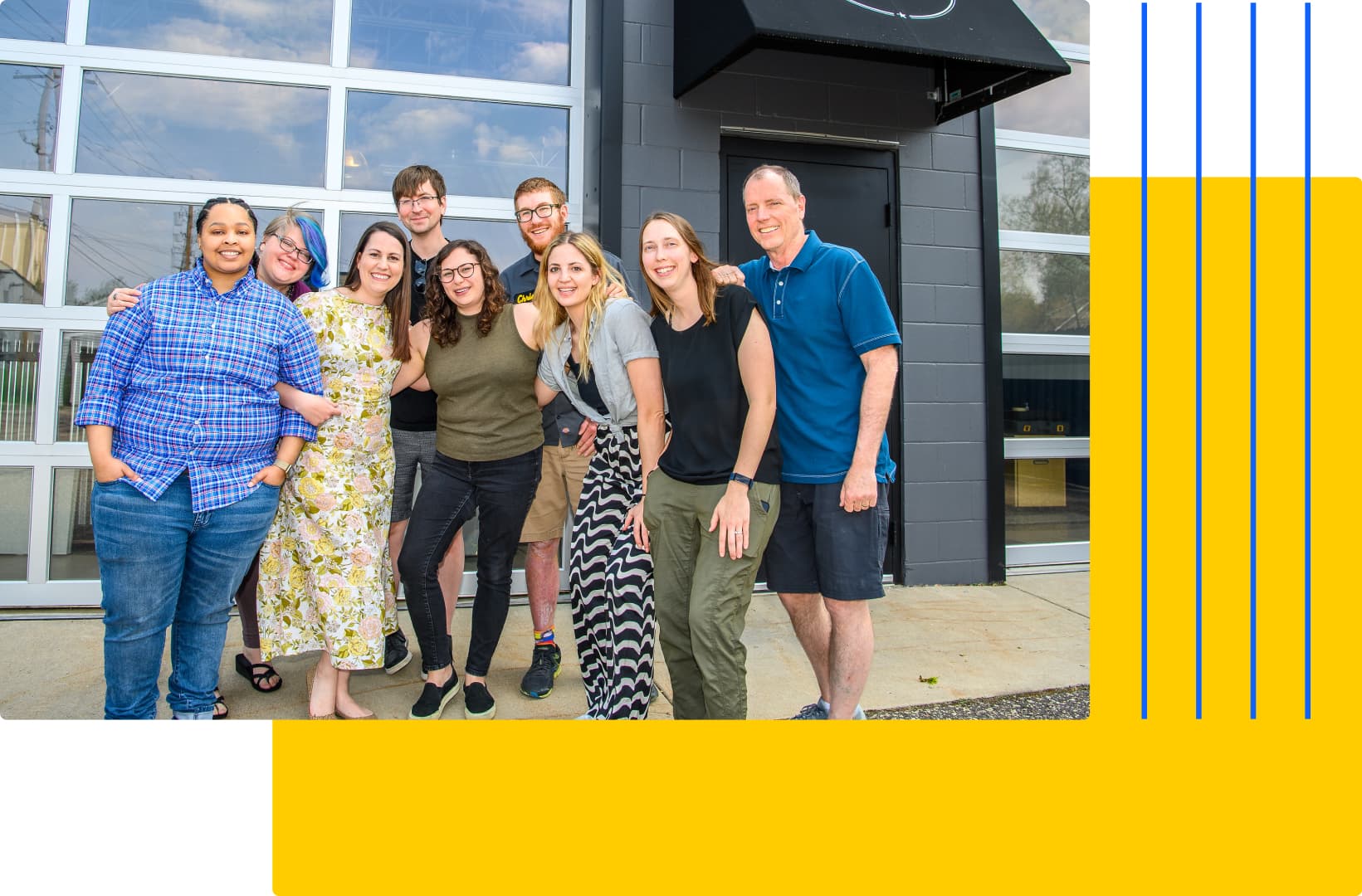A group of nine people stands smiling outside a building with a glass-paneled door, embodying the spirit of a team dedicated to creating custom software. Casually dressed, some sport glasses, while yellow and blue graphic elements adorn the background.