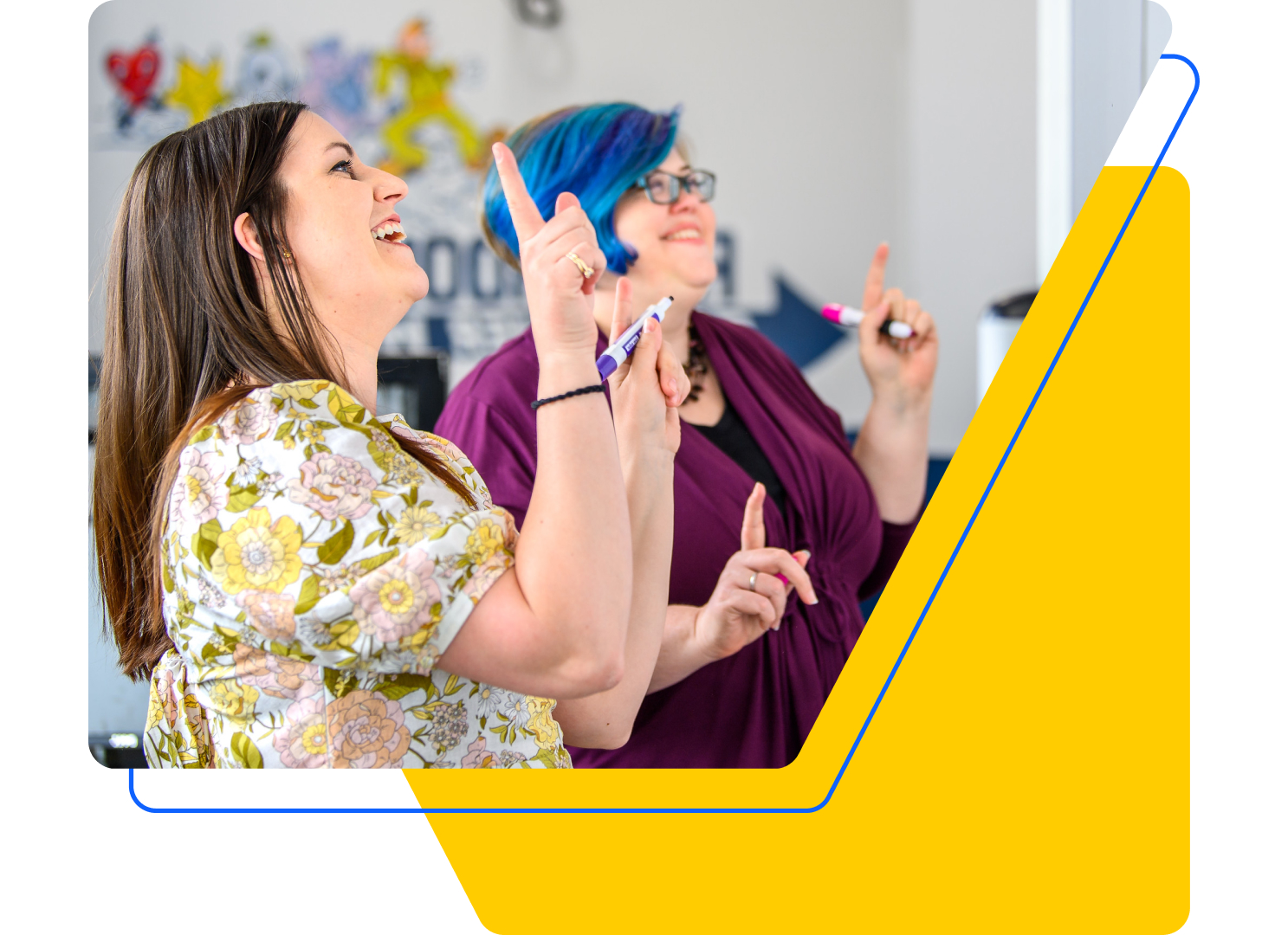 Two people, one with long brown hair and a floral shirt, the other with short blue hair and a purple top, are smiling and pointing at a whiteboard. They seem engaged in custom software experience design. Bright yellow geometric shapes frame the image.