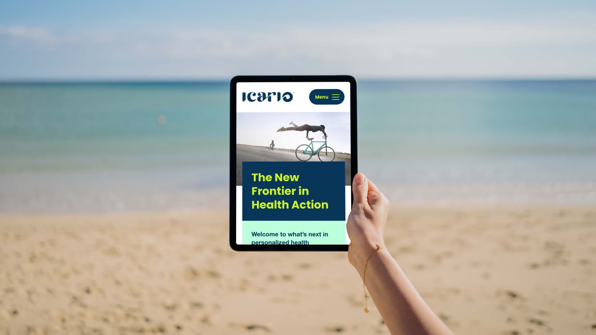 A person holds a tablet on a beach, displaying a website with the title The New Frontier in Health Action. With the calm sea and clear sky as a backdrop, this blend of experience design and serene nature creates an immersive customer experience.