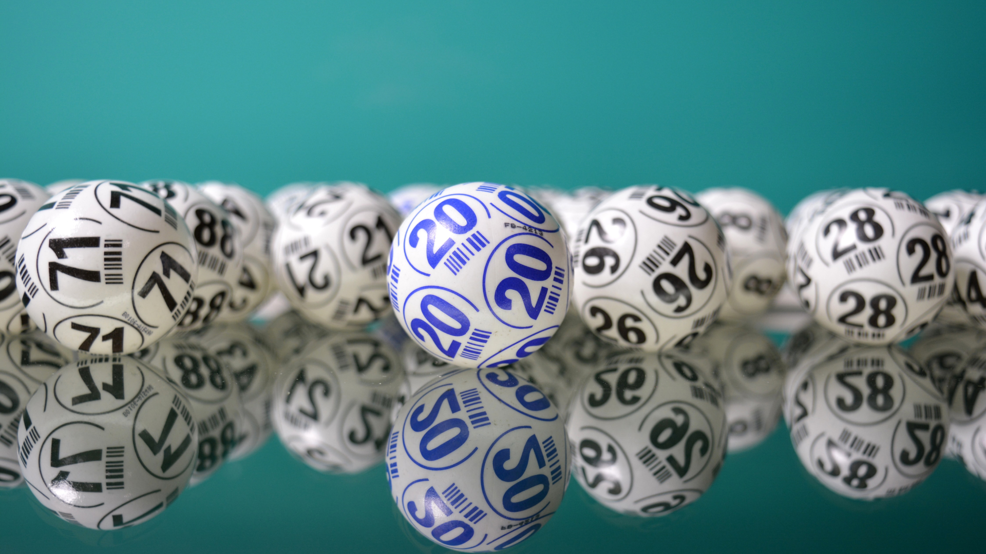 Lottery balls with numbers, including a highlighted blue ball marked 20, are artfully scattered on a reflective surface against a teal background, creating an engaging user experience that could inspire innovative digital solutions.